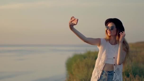 Mujer joven haciendo selfie en el borde de un acantilado cerca del río — Vídeos de Stock