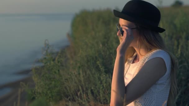 Jeune femme en lunettes de soleil assis sur le bord d'une falaise profitant de la nature — Video