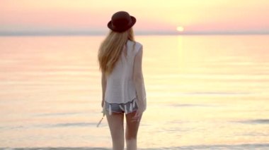 Yaz tatillerini okyanus altın günbatımı üzerinde zevk şapkalı genç sarışın kız
