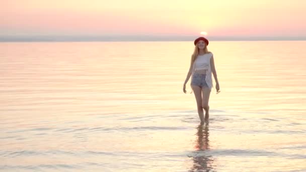 Jovem loira de chapéu desfrutando de férias de verão no oceano pôr do sol dourado — Vídeo de Stock