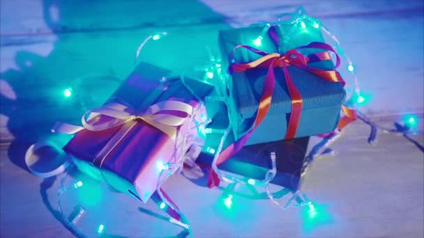 Закройте новогодние подарки синей мигающей гирляндой — стоковое видео