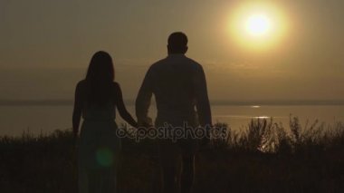 Mutlu çift deniz kenarında doğa günbatımı üzerinde yürürken. Aşk kavramı.