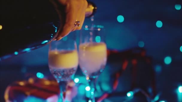 Champagne coulant de la bouteille, deux flûtes à vin mousseux bokeh clignotant — Video