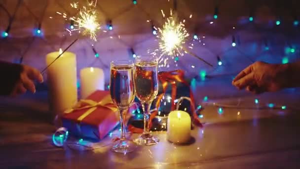 Ruce s prskavky na pozadí vánočních dárků svíčky a champagne