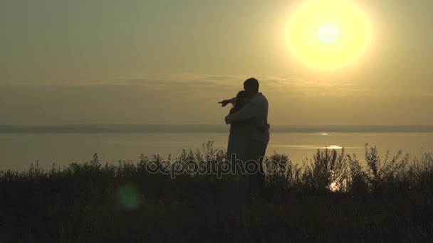 Feliz joven pareja mira el mar en el atardecer hombre mostrar algo a su mujer — Vídeos de Stock