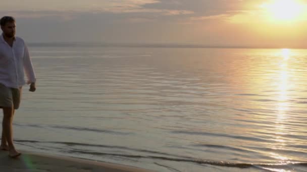 Joven pareja feliz caminando cerca del mar al atardecer. Concepto de amor . — Vídeo de stock