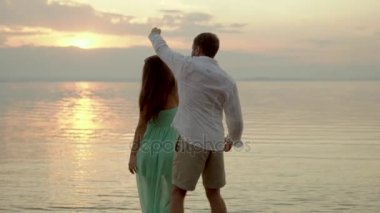 Genç mutlu çift sahilde günbatımı üzerinde dans. Aşk kavramı.