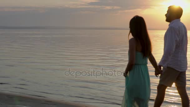 Junges glückliches Paar beim Spaziergang am Meer bei Sonnenuntergang. Konzept der Liebe. — Stockvideo