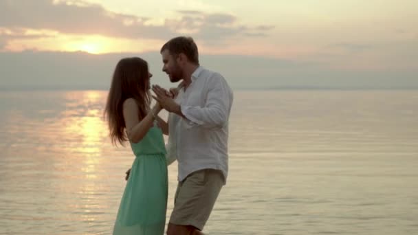 Junges glückliches Paar, das am Strand im Sonnenuntergang tanzt. Konzept der Liebe. — Stockvideo