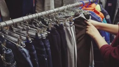 Kadın el ikinci el dükkanı çocuk için bir pantolon seçer