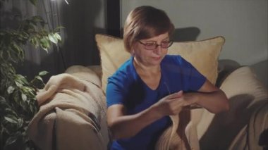 Yaşlı kadın evde oturur ve eşarp dokuma kumaşlar