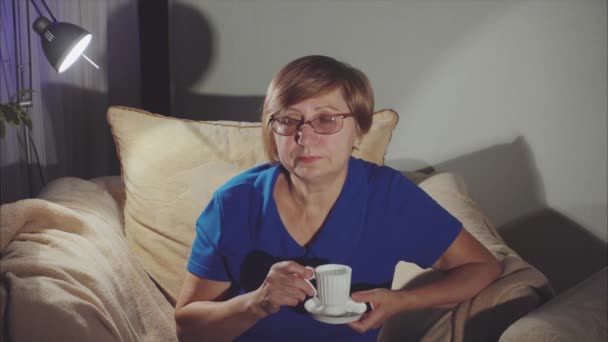 Mujer mayor bebiendo té sentada en la silla — Vídeos de Stock