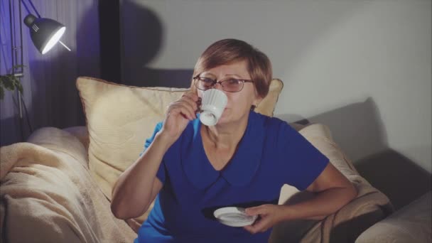 Seniorin sitzt auf dem Stuhl und trinkt Tee — Stockvideo