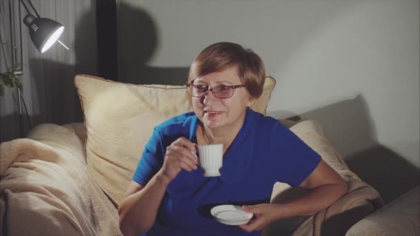 Mulher idosa feliz sorrindo, sentada na poltrona bebendo chá — Vídeo de Stock