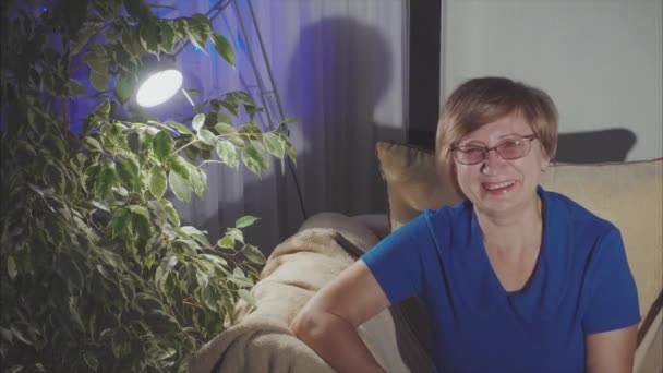 Porträt einer lachenden älteren Frau, die zu Hause auf dem Sessel sitzt — Stockvideo