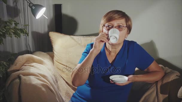 Nachdenkliche Seniorin trinkt Kaffee aus weißer Tasse — Stockvideo