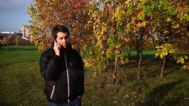 Telefonda konuşurken sonbahar parkta yürüyüş siyah ceketli genç adam