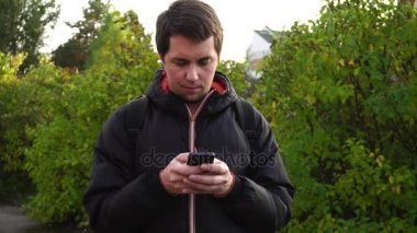 Siyah ceketli genç adam onun smartphone açık kullanarak Internet sörf