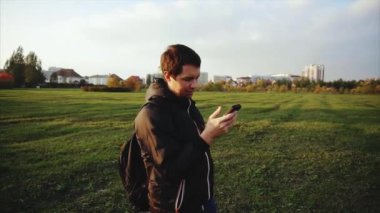 Siyah ceketli genç adam onun smartphone açık kullanarak Internet sörf