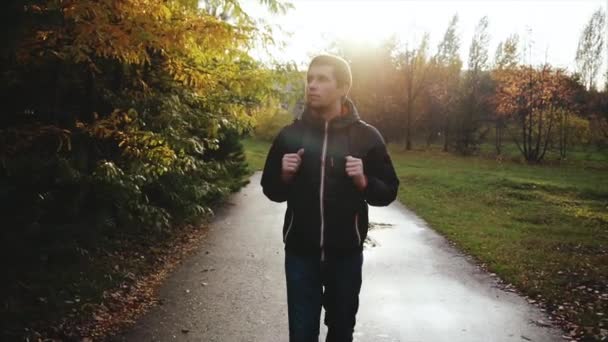 Jovem homem calmo de casaco preto andando no parque de outono — Vídeo de Stock