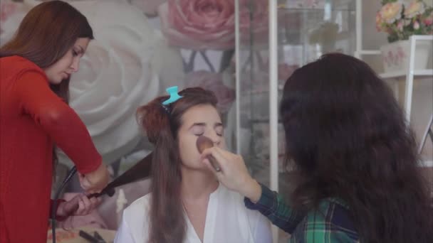 Haarstylist en make-up artist werken bij afbeelding model. — Stockvideo