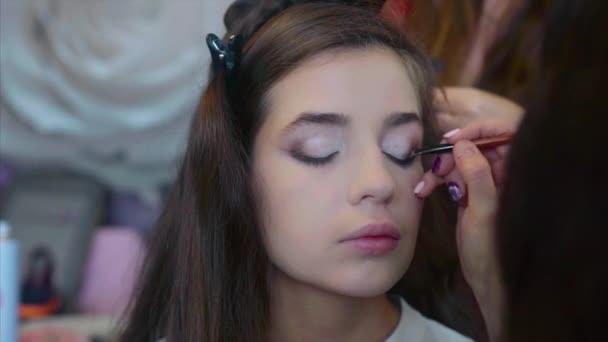 Maquillaje artista aplicación de sombra de ojos, mientras que el estilista haciendo pelo-do . — Vídeos de Stock