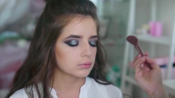 Make-up artiest van toepassing blozen op de jukbeenderen model — Stockvideo
