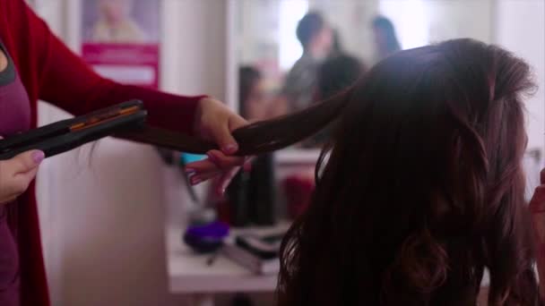 Primer plano de peluquero haciendo pelo-do con plancha de pelo cámara lenta — Vídeo de stock