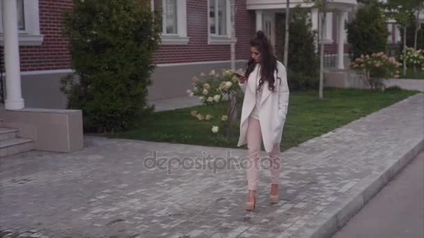 Jonge sexy succesvolle vrouw lopend onderaan de straat met haar smartphone — Stockvideo