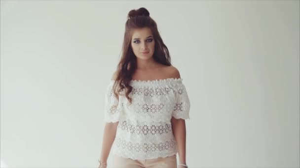 Young woman brunette posing in studio on white background and walking to camera — Stock Video