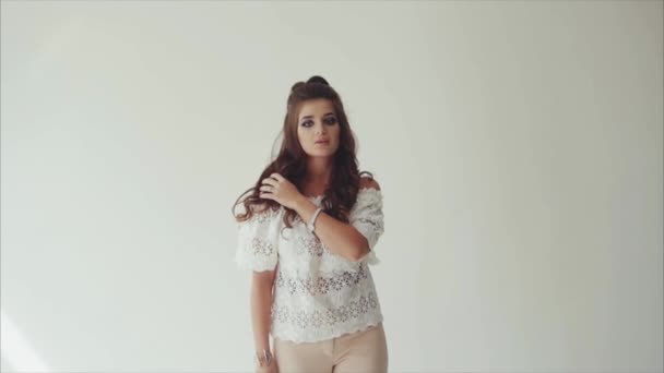 Vacker kvinna poserar i studio på vit bakgrund och gångavstånd till kameran — Stockvideo
