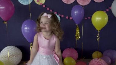 Gülüyor ve bir öpücük doğum günü partisi üzerinde üfleme sevimli küçük bebek kız