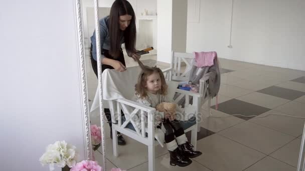 Peluquero haciendo rizos usando una plancha para el cabello a la niña bonita ser hermosa — Vídeo de stock