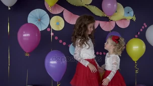 Две хорошенькие девочки-сестры обнимаются и празднуют день рождения — стоковое видео