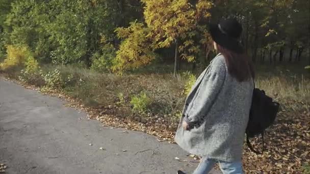 Jonge mooie vrouw in zwarte hoed en bril lopend onderaan de straat herfst — Stockvideo