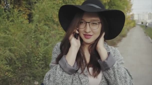 Młoda ładna kobieta w czarny kapelusz i okulary wywołanie jej przyjaciel odkryty — Wideo stockowe