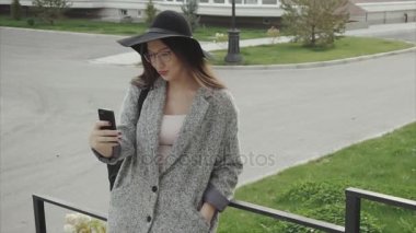 Siyah şapka ve gözlük manifatura smartphone cep telefonu ile açık güzel kadın