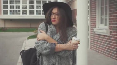 Siyah şapka ve sokakta yürürken kahve Kupası ile gözlük güzel kadın