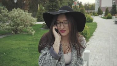 Siyah şapka ve gözlük bir Şehir Parkı içinde cep telefonu konuşurken genç kadın