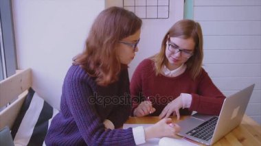 Bayan üniversite öğrencileri kafede okuyor. İki kız arkadaş birlikte öğreniyor.