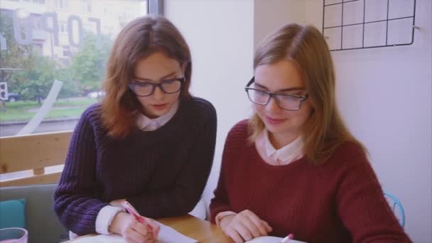 Női főiskolai hallgatók tanulnak a kávézóban két lány barátok tanul együtt — Stock videók