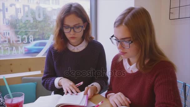 Bayan üniversite öğrencileri kafede okuyor. İki kız arkadaş birlikte öğreniyor. — Stok video