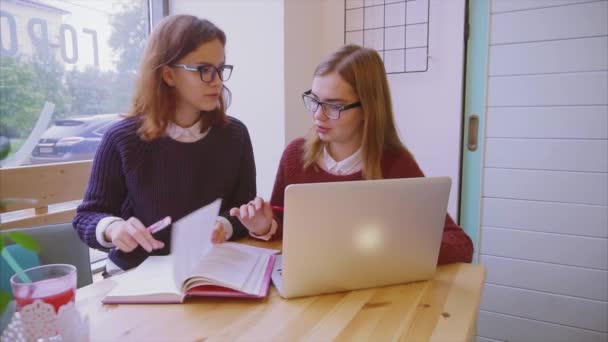 Estudiantes universitarias estudian en la cafetería dos amigas aprendiendo juntas — Vídeo de stock