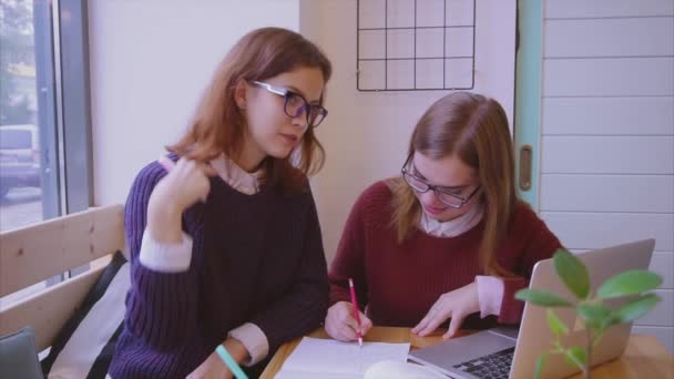 Estudiantes universitarias estudian en la cafetería dos amigas aprendiendo juntas — Vídeo de stock