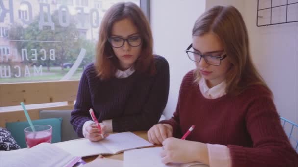 Vrouwelijke studenten studeren in het café twee meisjes vrienden leren samen — Stockvideo