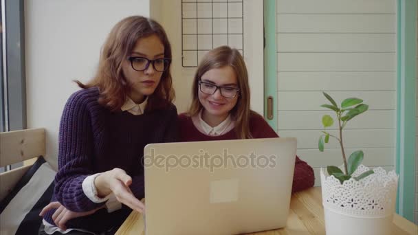 Две девушки разговаривают с друзьями через веб-чат или видео-чат в кафе — стоковое видео