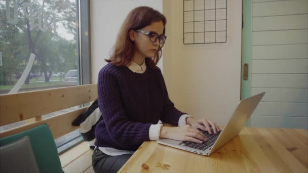 Ung kvinna student med modern laptop sitter i café — Stockvideo