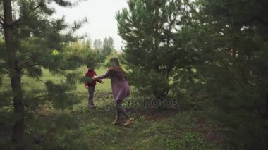 Anne ve kızı sonbahar ormanında yürüyor.