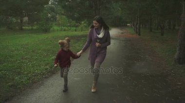 Anne ve kızı sonbahar parkta çalıştıran