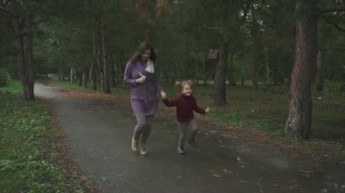 Anne ve kızı sonbahar parkta çalıştıran